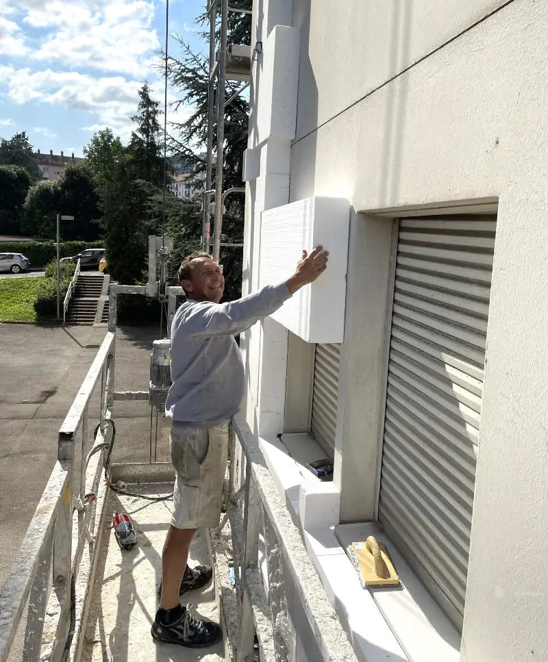 Un membre de l'équipe Moyse 3D en train de poser l'isolation thermique par l'extérieur d'un bâtiment